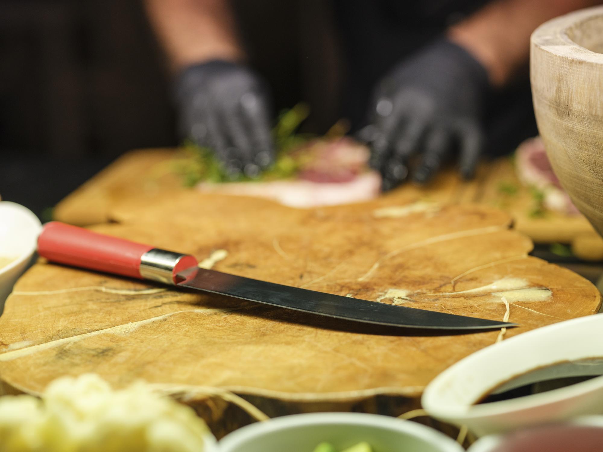 Instructor demonstrating knife skills on a wooden board
